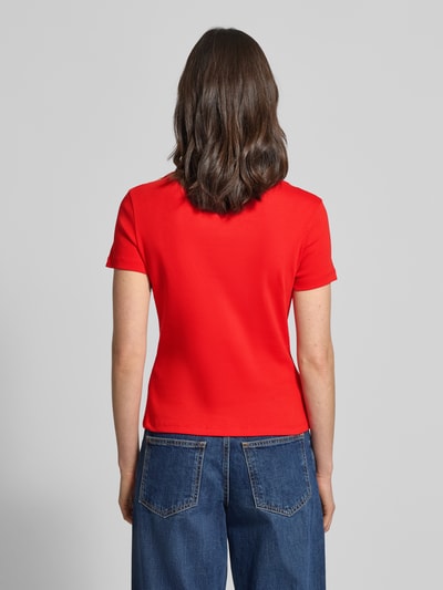 Frauenmodel trägt Slim Fit T-Shirt aus reiner Baumwolle von Tommy Hilfiger, Optik: Unifarben, Passform: Slim-Fit, Logo-Detail, Zierknöpfe, U-Boot-Ausschnitt, Ärmelform: Kurzarm, Ärmelabschluss: Gerade, Materialverarbeitung: Webware, Farbe Rot, Ganzkörperansicht Rückansicht.