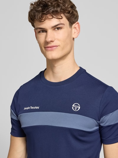 Männermodel trägt Regular Fit T-Shirt mit Logo-Print Modell 'Leone' von SERGIO TACCHINI in Dunkelblau mit Rundhalsausschnitt, Nahaufnahme Oberkörper.