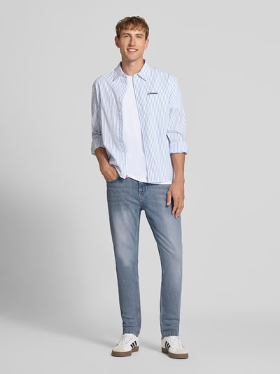 Männermodel trägt Tapered Fit Jeans aus Baumwoll-Mix von Marc O'Polo Denim in Hellblau, kombiniert mit weiß-blauer Hemdstruktur, Ganzkörperansicht von vorne. Herren Tapered Fit Jeans von Marc O'Polo Denim