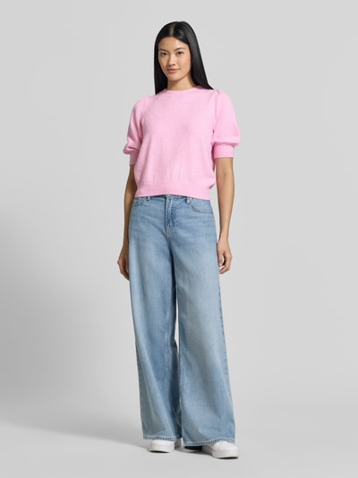 Frauenmodel trägt Regular Fit Pullover mit Puffärmeln von VERO MODA in Rosa zu weiter Jeans, glatte Textur, Ganzkörperansicht von vorne.