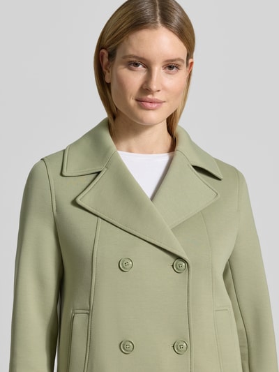 Vrouwenmodel draagt Regular Fit sweatjack met viscose van s.Oliver RED LABEL in lichtgroen, dubbele knoopsluiting, reverskraag, zijssteekzakken, capuchon, sweat materiaalverwerking, detailopname bovenlichaam.