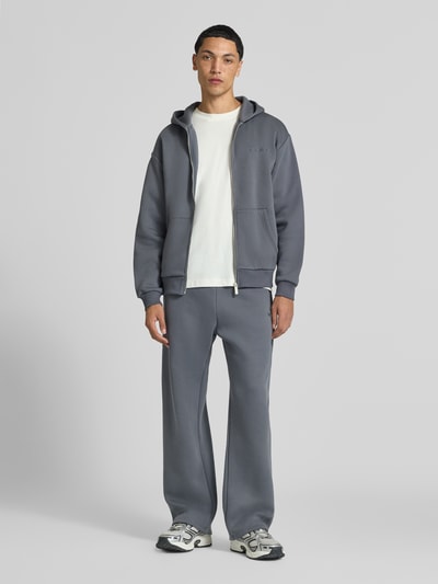 Männermodel trägt Sweatpants mit Logo-Print und Gesäßtasche von REVIEW, Baumwoll-Mix, gerader Schnitt, Ganzkörperansicht von vorne.