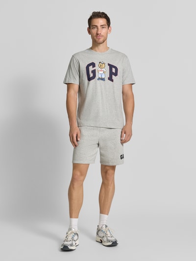 Męski model nosi Regular Fit T-Shirt mit Logo-Print od GAP, szary, bawełna, krój regular fit, okrągły dekolt, Długość tyłu w rozmiarze M: 62 cm, Ganzkörperansicht von vorne