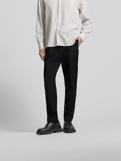 Männermodel trägt Straight Fit Stoffhose aus reiner Wolle von Officine Générale in Schwarz mit Bundfalten und Taschen, Nahaufnahme Unterkörper.