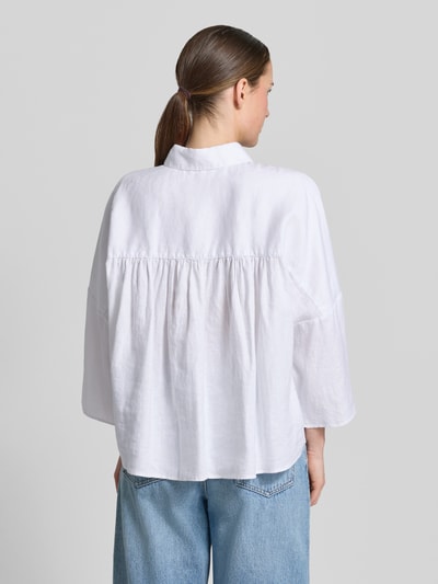 Frauenmodel trägt Leinenbluse mit überschnittenen Schultern von Christian Berg Woman in Weiß, reine Leinenqualität, Loose-Fit, Kentkragen, Knopfleiste, 3/4-Arm, Rückenlänge bei Größe 36: 63 cm, Ärmellänge: 54 cm, Ganzkörperansicht Rückansicht.