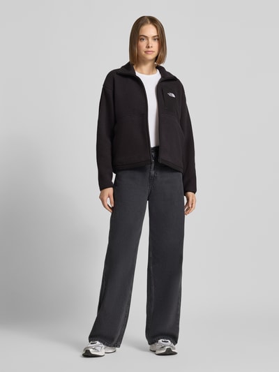 Frauenmodel trägt Regular Fit Fleecejacke mit Stehkragen Modell 'YUMIORI' von The North Face in Schwarz, sportlich, Logo-Stitching, Ganzkörperansicht von vorne.