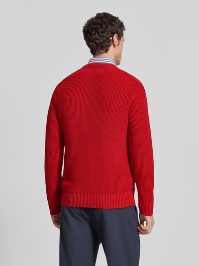 Männermodel trägt Regular Fit Strickpullover aus reiner Baumwolle von MCNEAL in Rot mit elastischen Abschlüssen, Ganzkörperansicht Rückansicht.