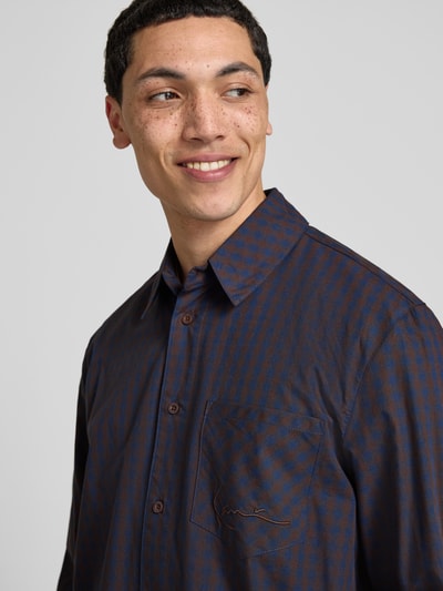 Mannelijk model draagt Relaxed Fit vrijetijdsoverhemd met borstzak van KARL KANI, puur katoen, gestikt logo, kentkraag, knoopsluiting, langärmelig; Nahaufnahme Oberkörper.