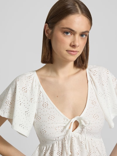 Modelka kobieca nosi Slim Fit T-Shirt mit tiefem V-Ausschnitt Modell 'SMILLA' von Only, biały, semitransparentny, kwiatowy wzór, krótki rękaw, materiał stretch, krój slim fit, zbliżenie górnej części ciała