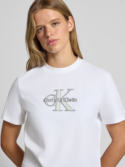 Frauenmodel trägt Regular Fit T-Shirt aus reiner Baumwolle von Calvin Klein Jeans in Weiß mit Logo, Nahaufnahme Oberkörper.