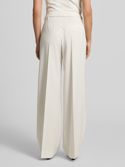 Frauenmodel trägt Loose Fit Weite Hose mit Viskose-Anteil Modell 'HEJULY' von HUGO in creme mit feinem Streifenmuster, Twillstruktur, Bundfalten, Gürtelschlaufen und angedeuteten Gesäßtaschen, Ganzkörperansicht Rückansicht.