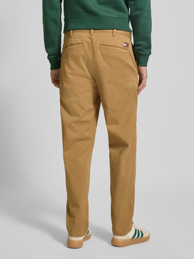 Männermodel trägt Tapered Chino aus Baumwoll-Mix Modell 'SONNY' von Tommy Jeans, efekt: jednolity kolor, krój regular fit, szlufki na pasek, zapięcie na guzik i ukryty zamek błyskawiczny, wpuszczane kieszenie boczne, kieszenie z tyłu, kieszonka na monety, wykończenie materiału: splot twill, mieszanka bawełny, całkowity widok z tyłu.