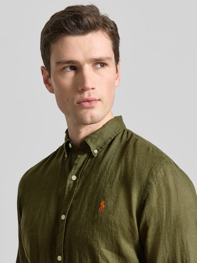 Männermodel trägt Slim Fit Freizeithemd aus reinem Leinen von Polo Ralph Lauren in Olivgrün mit Logo-Detail, Nahaufnahme Oberkörper.
