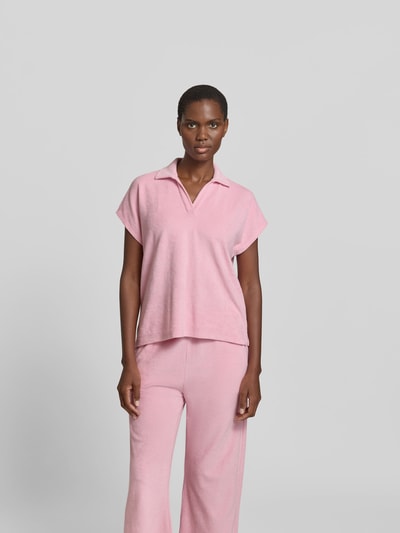 Frauenmodel trägt Poloshirt in Frottee-Optik von Juvia in Rosa, Baumwoll-Mix, Relaxed-Fit, Polokragen, kurzärmelig, Ganzkörperansicht von vorne.