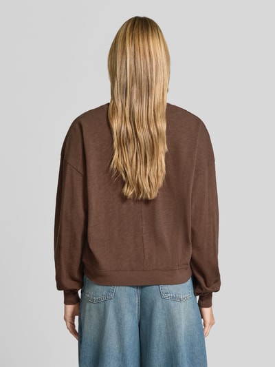 Frauenmodel trägt Relaxed Fit Sweatshirt aus reiner Baumwolle von American Vintage, braun, elastische Bündchen, Rundhalsausschnitt, Langarm, Rückenlänge 57 cm, Ganzkörperansicht Rückansicht.