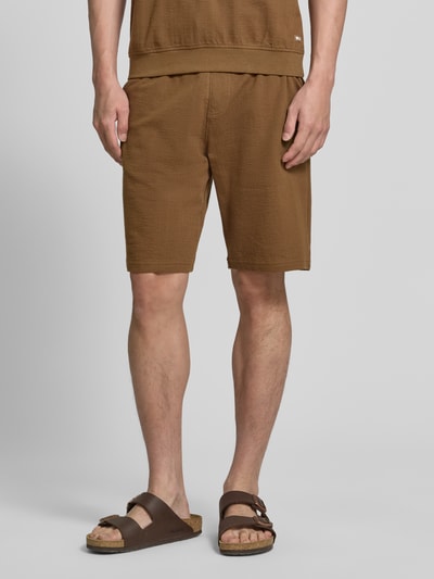 Männermodel trägt Relaxed Fit Sweatshorts aus reiner Baumwolle Modell 'DETROIT' von s.Oliver RED LABEL in Braun, fein strukturiert, unifarben, elastischer Bund, seitliche Eingrifftaschen, Gesäßtasche, Ganzkörperansicht von vorne.