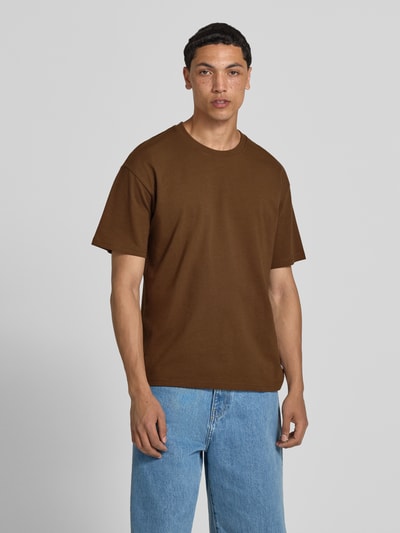 Męskimodell trägt Regular Fit T-Shirt mit Rundhalsausschnitt von Jack & Jones, bawełna, krój regular fit, rękaw o dł. 1/2, długość tyłu w rozmiarze M 70 cm, brązowa koszulka z niebieskimi jeansami, Ganzkörperansicht von vorne