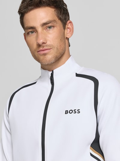 Männermodel trägt Regular Fit Trainingsjacke mit Kontrastdetails von BOSS Green, Mehrfarbig, Stehkragen, Label-Print, Nahaufnahme Oberkörper.