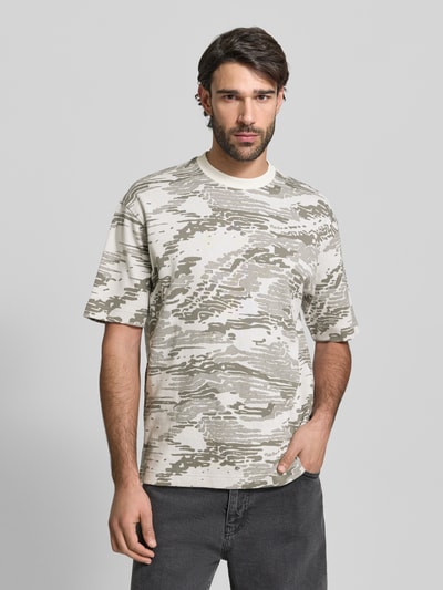 Männermodel trägt Regular Fit T-Shirt aus reiner Baumwolle Modell 'TE_WILDNATURE' von BOSS Orange mit abstraktem Allover-Muster, Feinstrick, kurzarm, Label Patch, Rundhalsausschnitt; neutrale Naturtöne, Ganzkörperansicht von vorne.