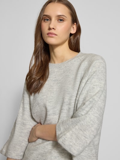 Frauenmodel trägt Oversized Strickpullover mit 3/4-Arm Modell 'SIMONI' von Only in melange-grauer Strickoptik, Nahaufnahme Oberkörper.