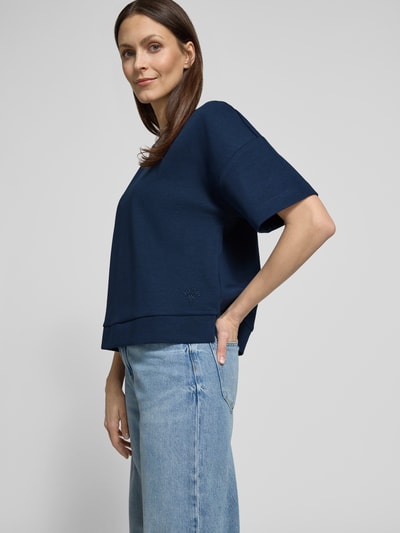 Frauenmodel trägt Boxy Fit T-Shirt Modell 'Tilina' von JOOP! aus Baumwoll-Mix mit Rundhalsausschnitt in Dunkelblau, Nahaufnahme Oberkörper.