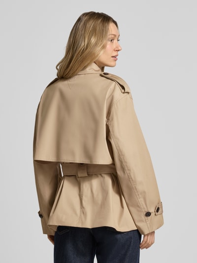 Modelka nosi Regular Fit Trenchcoat aus reiner Baumwolle von Tommy Hilfiger w kolorze beżowym, krój regular fit, tkanina twill, detal logo, pasek, widok całej sylwetki z tyłu.