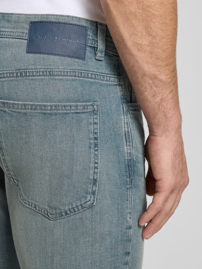 Mężczyzna model nosi Regular Fit Jeans Bermudas aus Baumwoll-Mix von Tom Tailor, denim, krój regular fit, bawełniany materiał, detal: label patch, widok z tyłu, zbliżenie na tylną kieszeń.