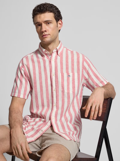 Männermodel trägt Regular Fit Freizeithemd aus Leinen-Baumwoll-Mix von Gant mit rosa-weißen Streifen, Brusttasche, Nahaufnahme Oberkörper.