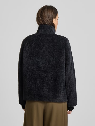 Vrouwenmodel draagt Jacke mit Kunstfell van comma, los model, zwarte kunstvacht, elastische manchetten, rugaanzicht, detailmix zichtbaar.