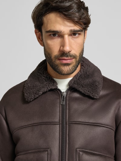 Männermodel trägt Blouson in Leder-Optik mit Zweiwege-Reißverschluss von Armani Exchange, braune Farbe, Teddyfellkragen, krój regular fit, Nahaufnahme Oberkörper