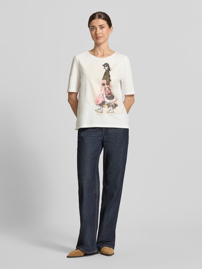 Modelka kobieca ma na sobie T-Shirt mit Motiv-Print und Pailletten od Oui, biała bawełna, krój regular fit, motyw i cekiny, okrągły dekolt, długość tyłu w rozmiarze 36: 58 cm, cała sylwetka z przodu.