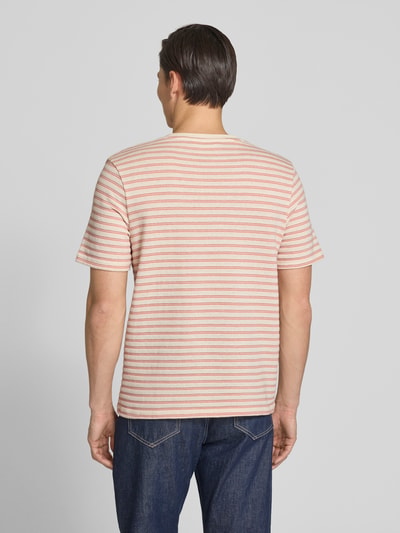 Mannenmodel draagt Regular Fit T-Shirt uit katoenmix model 'KEVIN' van SELECTED HOMME met all-over gestreept motief, fijn breisel, korte mouw, ronde hals, kleuren lichtroze en beige, recht model, rugaanzicht volledige lichaamsopname.
