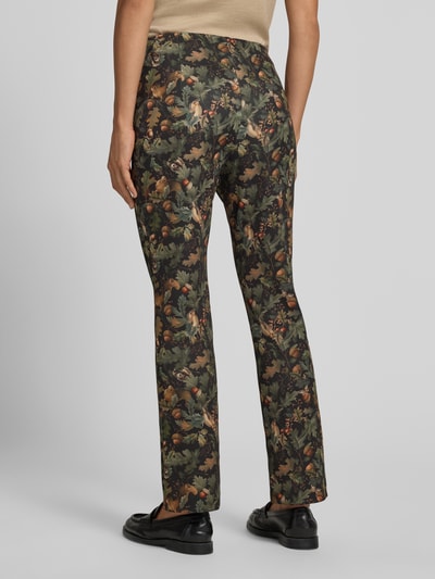 Kobieta nosi Flared Cut Hose im Allover-Look mit elastischem Bund od Marc Cain wykonane z mieszanki materiałów z dodatkiem streczu, wzór na całej powierzchni, elastyczny pas, szerokość w rozmiarze 36: 38 cm, długość wewnętrzna nogawki w rozmiarze 36: 72 cm, widok całej sylwetki z tyłu.