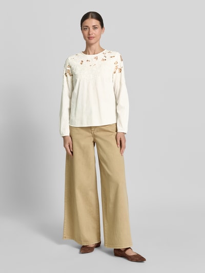 Modelka kobieca ma na sobie Bluse mit Spitze und Rundhalsausschnitt od Oui, biała bawełna, prosty krój, zaokrąglony dół, długość tyłu 55 cm, długość rękawa 59 cm, szerokie beżowe spodnie, brązowe buty, pełny widok z przodu.