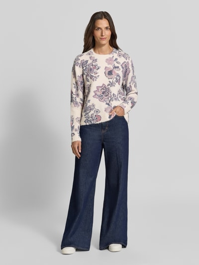 Vrouwenmodel draagt Relaxed Fit Strickpullover mit Leinen-Anteil van Christian Berg Woman, elastische materiaalmix met linnen, ribboorden, bies, lange mouw, ruglengte maat S 57 cm, mouwlengte maat S 62 cm, bloemmotief in lila en roze op licht beige, wijdvallende jeans, sneakers, zachte textuur, volle lichaamsaanzicht van voren.