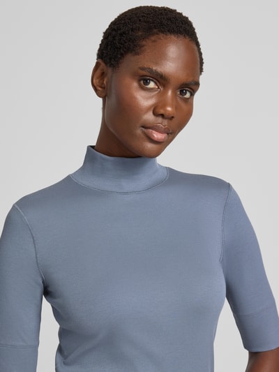 Frauenmodel trägt Slim Fit T-Shirt aus Baumwoll-Mix mit Stehkragen von Marc Cain in Hellblau, elastisch, Halbarm, Nahaufnahme Oberkörper.