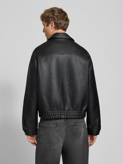 Männermodel trägt schwarze Jacke in Leder-Optik Modell 'NIGHTRIDER' von PROHIBITED, strukturierte Oberfläche, Ganzkörperansicht Rückansicht. Herren Jacke mit Logo, Reißverschluss, Regular Fit, Rückenlänge 65 cm, Schulterbreite 54 cm, Brustweite 62 cm, Ärmellänge 62 cm.