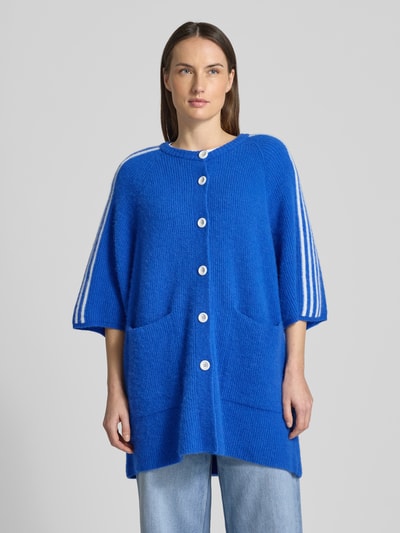 Frauenmodel trägt Strickjacke in Überlänge Modell 'VITOW' von American Vintage in Blau, lockerer Schnitt, gerippte Abschlüsse, Ganzkörperansicht von vorne.