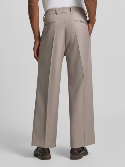 Männermodel trägt Wide Fit Hose mit Bügelfalten von Drykorn aus Baumwoll-Mix mit Stretch-Anteil, Beige, Ganzkörperansicht Rückansicht.