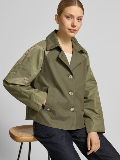 Vrouwenmodel draagt Trenchcoat met steekzakken model 'Zyla Neola' van MOS MOSH in katoenmengsel, regular fit, olijfgroen, knoopsluiting, omgeslagen kraag, vooraanzicht bovenlichaam.