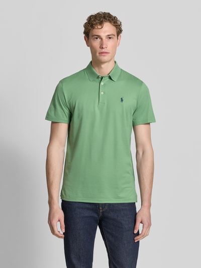 Männermodel draagt Regular Fit poloshirt uit katoenmix model 'TOUR PIQUE' van Polo Ralph Lauren, look: effen, logodetail, polokraag, v-hals, korte knoopsluiting, korte mouw, rompzoom met zijsplitten, piqué, kleur groen, materiaalverwerking: katoenmix. Ganzkörperansicht von vorne.