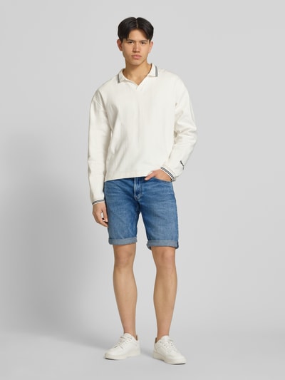 Männermodel trägt Jeansshorts mit Umschlag Modell 'Mosa' von G-Star Raw in Blau mit Used-Look, Regular Fit, Ganzkörperansicht von vorne.