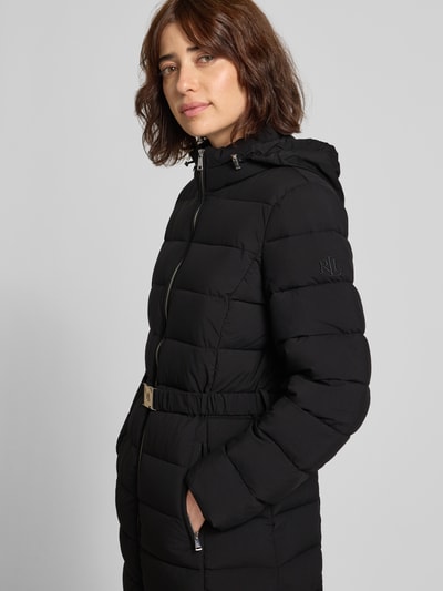 Frauenmodel trägt Taillierter Steppmantel mit Kapuze von Lauren Ralph Lauren in Schwarz, gesteppte Struktur, Ganzkörperansicht von vorne. Damen Steppmantel.