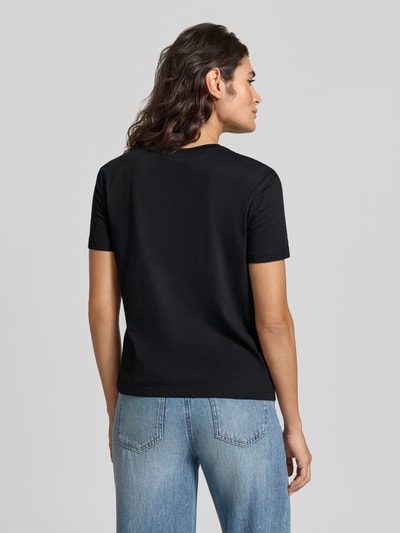 Modelka nosi Slim Fit T-Shirt mit Ziersteinbesatz von Liu Jo White z czarnej bawełny, okrągły dekolt, długość tyłu 57 cm, krój slim fit, widok całej sylwetki z tyłu.