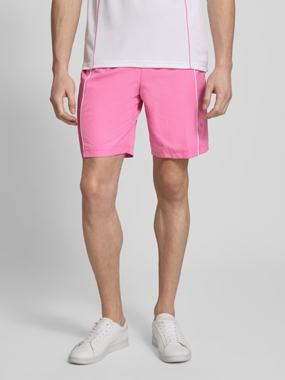Männermodel trägt Regular Fit Sport-Shorts mit weichem Innenstoff von Lacoste Sport; unifarben rosa, feines Strukturmuster, Ganzkörperansicht von vorne.