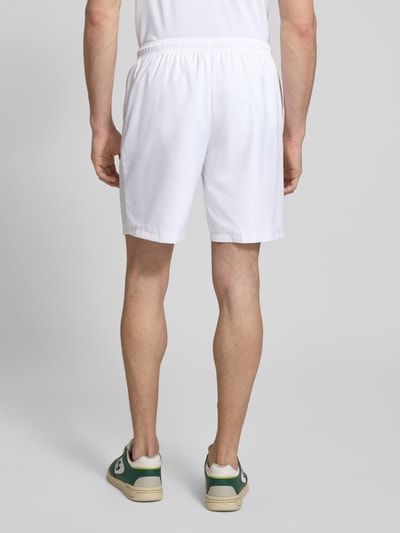 Męski model nosi Relaxed Fit Sport-Shorts mit Logo-Stitching od Lacoste Sport, białe, jednolite, elastyczny pas, kieszenie, widok całej sylwetki z tyłu.