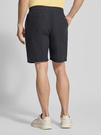 Männermodel trägt Shorts aus Baumwoll-Leinen-Mix Modell 'FAVE' von Scotch & Soda, Regular Fit, elastischer Bund, Rückansicht, Kontext Herren Shorts, Bundweite 42 cm, Innenbeinlänge 21 cm, dunkle Farbe, glatte Textur. Ganzkörperansicht Rückansicht.