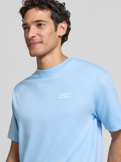 Männermodel trägt T-Shirt mit Statement-Print von MCNEAL, hellblau, lockerer Schnitt, Rundhalsausschnitt, Nahaufnahme Oberkörper.