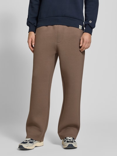 Männermodel trägt Regular Fit Sweatpants aus Material-Mix Modell 'BILL LEGACY' von JACK & JONES in Braun, Eingrifftaschen, elastischer Bund, Ganzkörperansicht von vorne, Herren Sweatpants, Material-Mix, Innenbeinlänge 77 cm, Größe M.