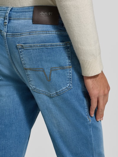 Mężczyznamodel nosi Jeansy z 5 kieszeniami Model 'Mitch' od JOOP! Jeans, mieszanka bawełny ze streczu, detal z logo, zapięcie na guzik i zamek, slim fit, jasnoniebieski denim, tekstura gładka, widok detaliczny tylnej kieszeni, zdjęcie w zbliżeniu tylnej części.